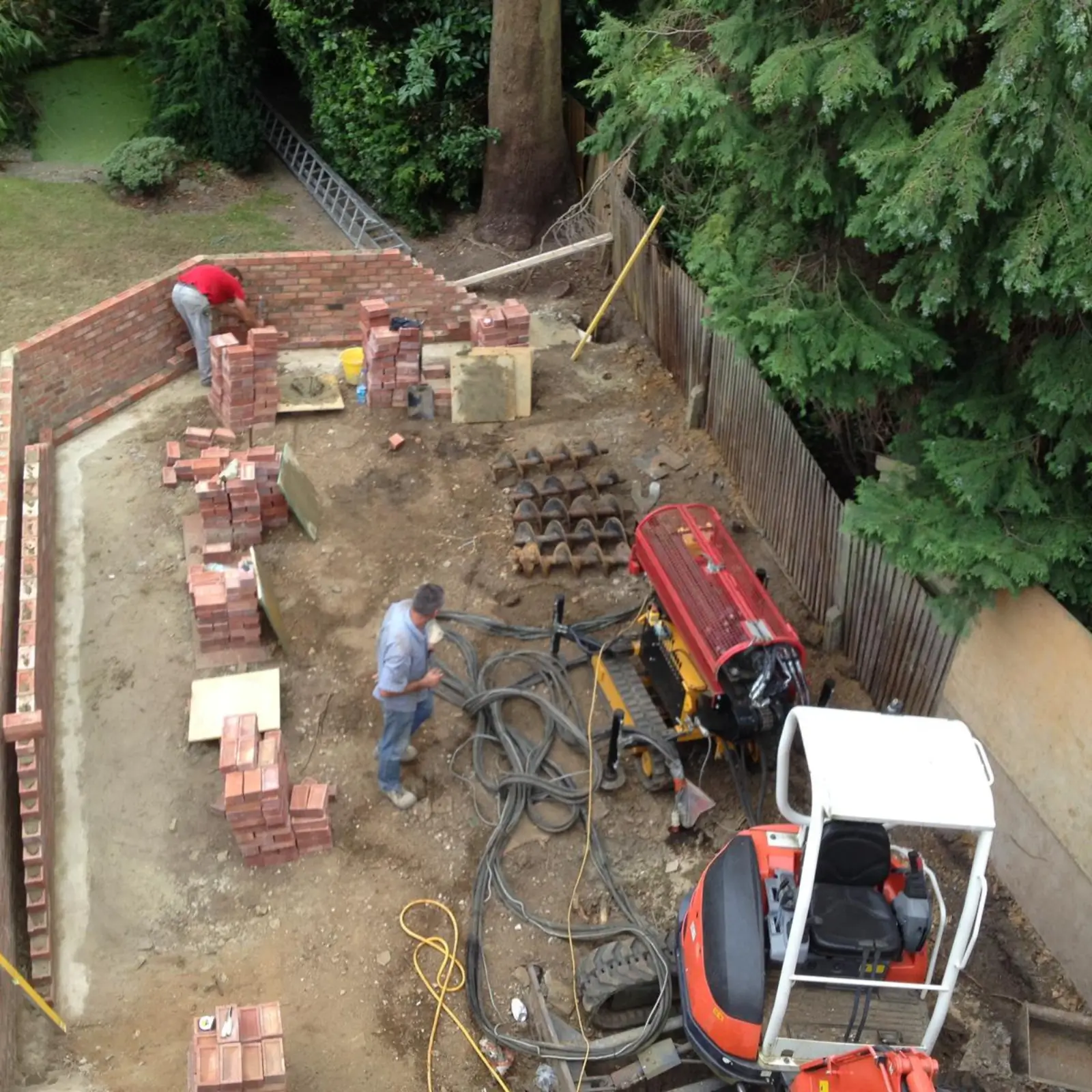 Workers building a basement foundation using brick and machinery.