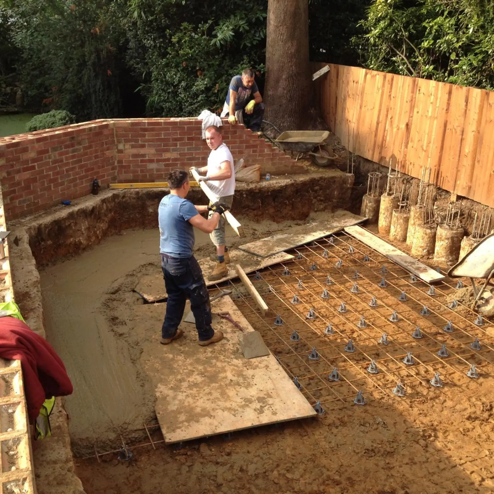 Construction crew laying groundwork and rebar for a foundation.