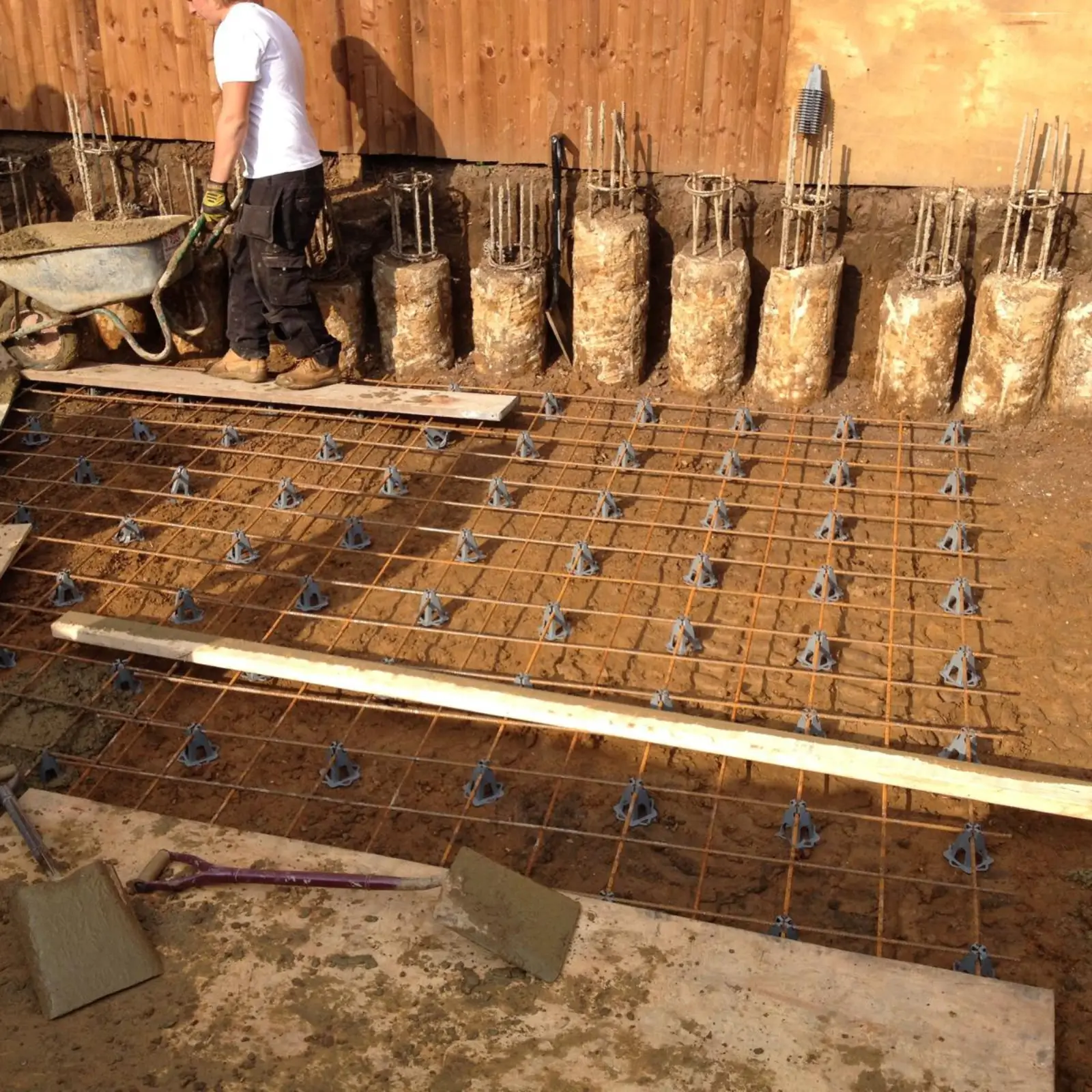 Worker preparing a foundation site with a rebar grid.