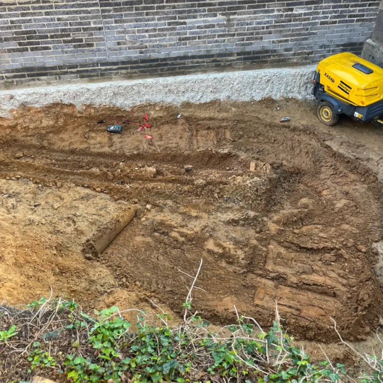 Underpinning work in progress next to a building foundation.