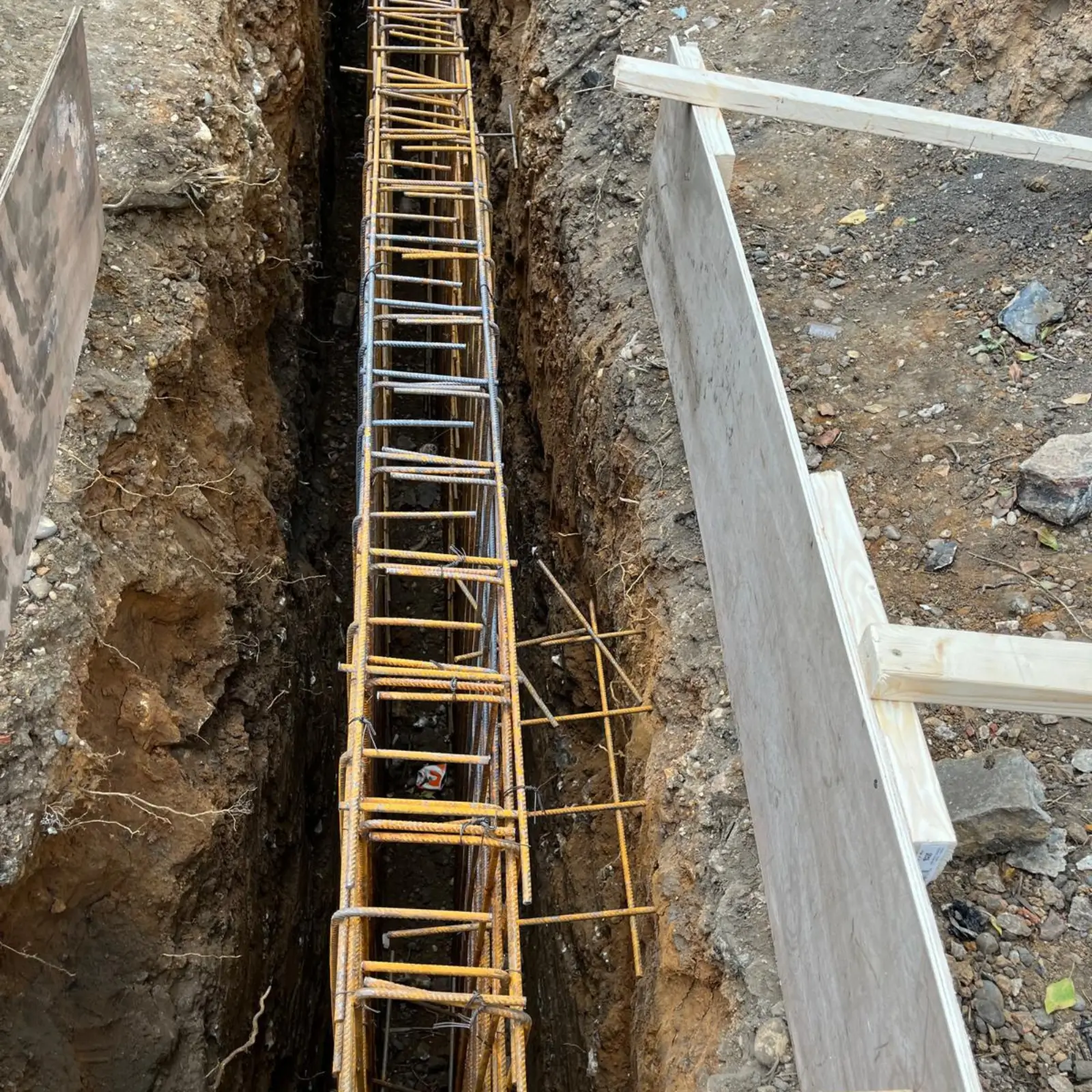 Rebar cage is lowered into a trench for rotary bored piling.