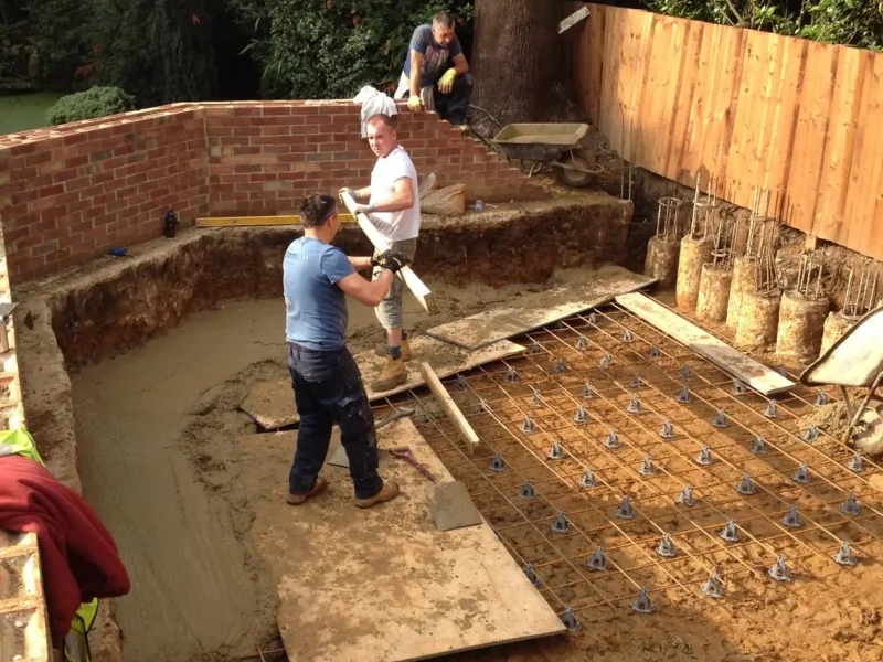goodman-mini-piling-groundwork-rebar. Construction crew laying groundwork and rebar for a foundation.
