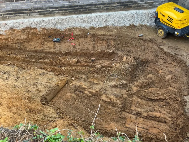Underpinning work in progress next to a building foundation.