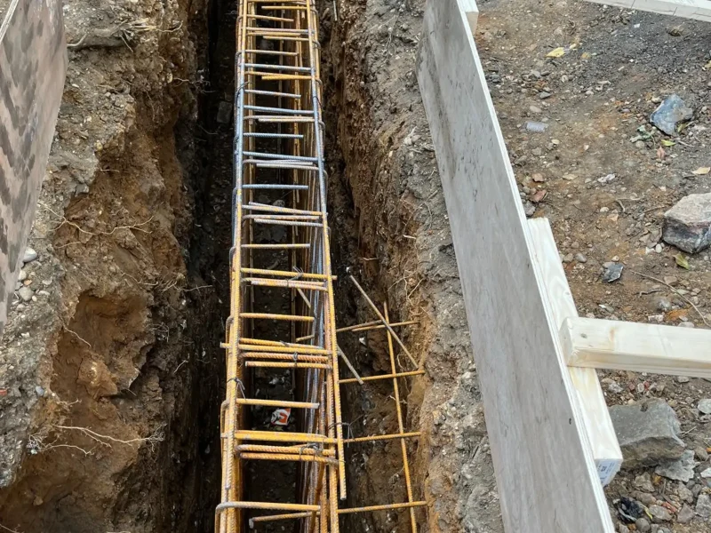 Rebar cage is lowered into a trench for rotary bored piling.